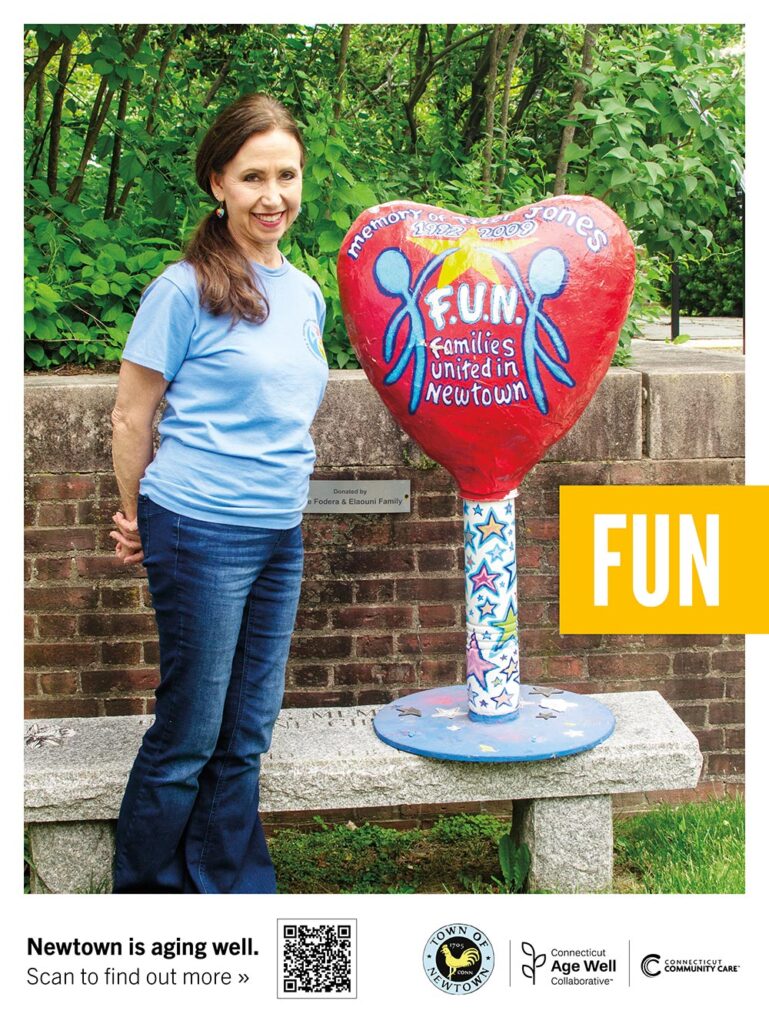 Linda standing next to her commemorative sculpture outside the Newtown Public Library