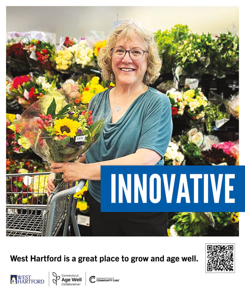 Robin stands in the florist area of a West Hartford grocery store, holding a bouquet of mixed summer flowers